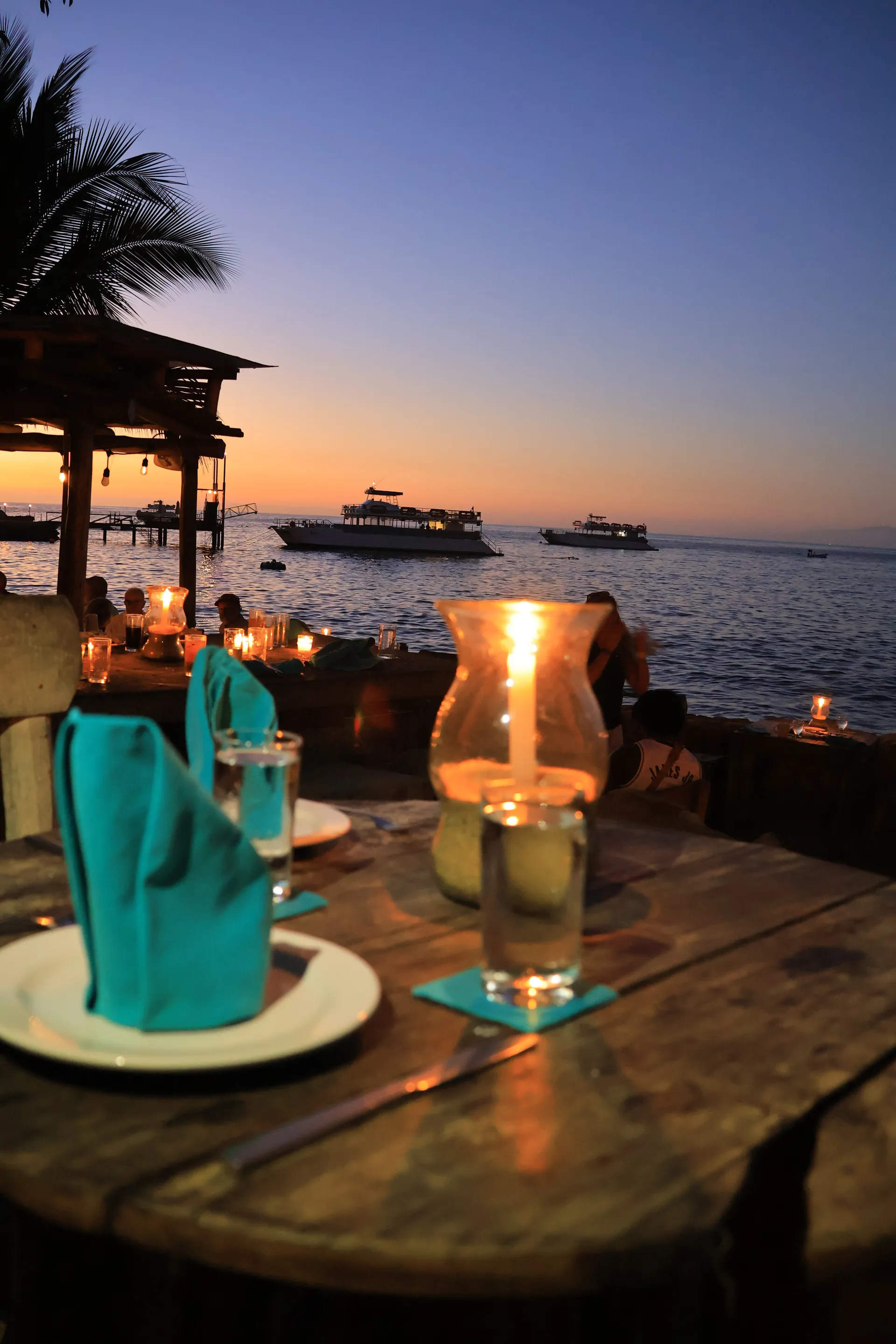 Oceanfront dining tables set at sunset for VIP guests at Las Caletas